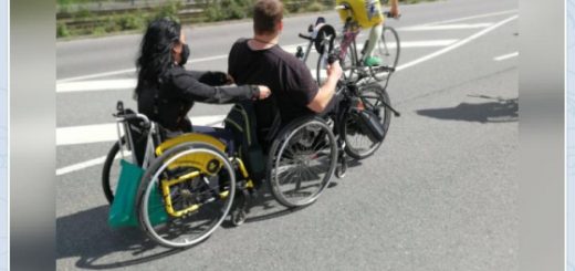 Handbikefahrer zieht eine Rollstuhlfahrerin bei einer Fahrraddemo