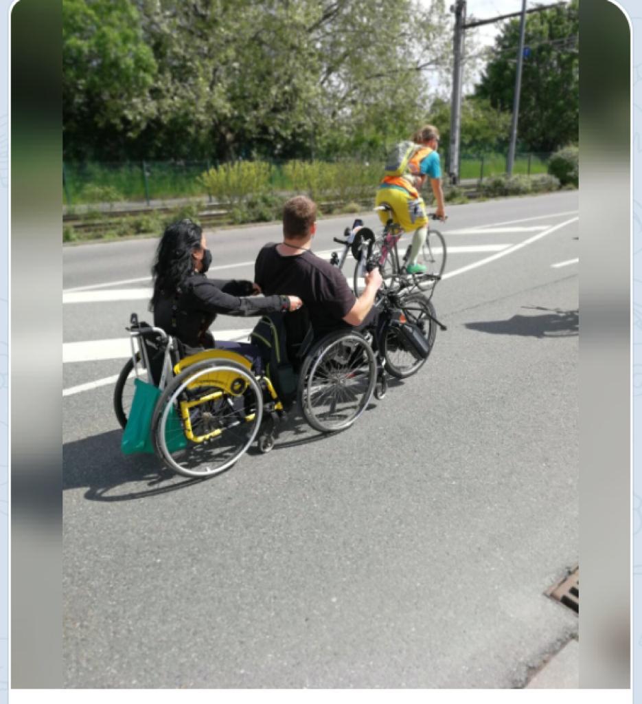 Handbikefahrer zieht eine Rollstuhlfahrerin bei einer Fahrraddemo