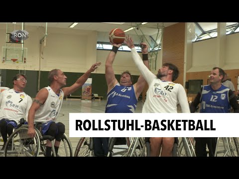 Vorschaubild des Interviews mit Christa Weber, drei weißgekleidete Rollstuhlbasketballer und zwei in blau, weiße Spieler beim Versuch der Abwehr des Wurfs eines blauen Spielers